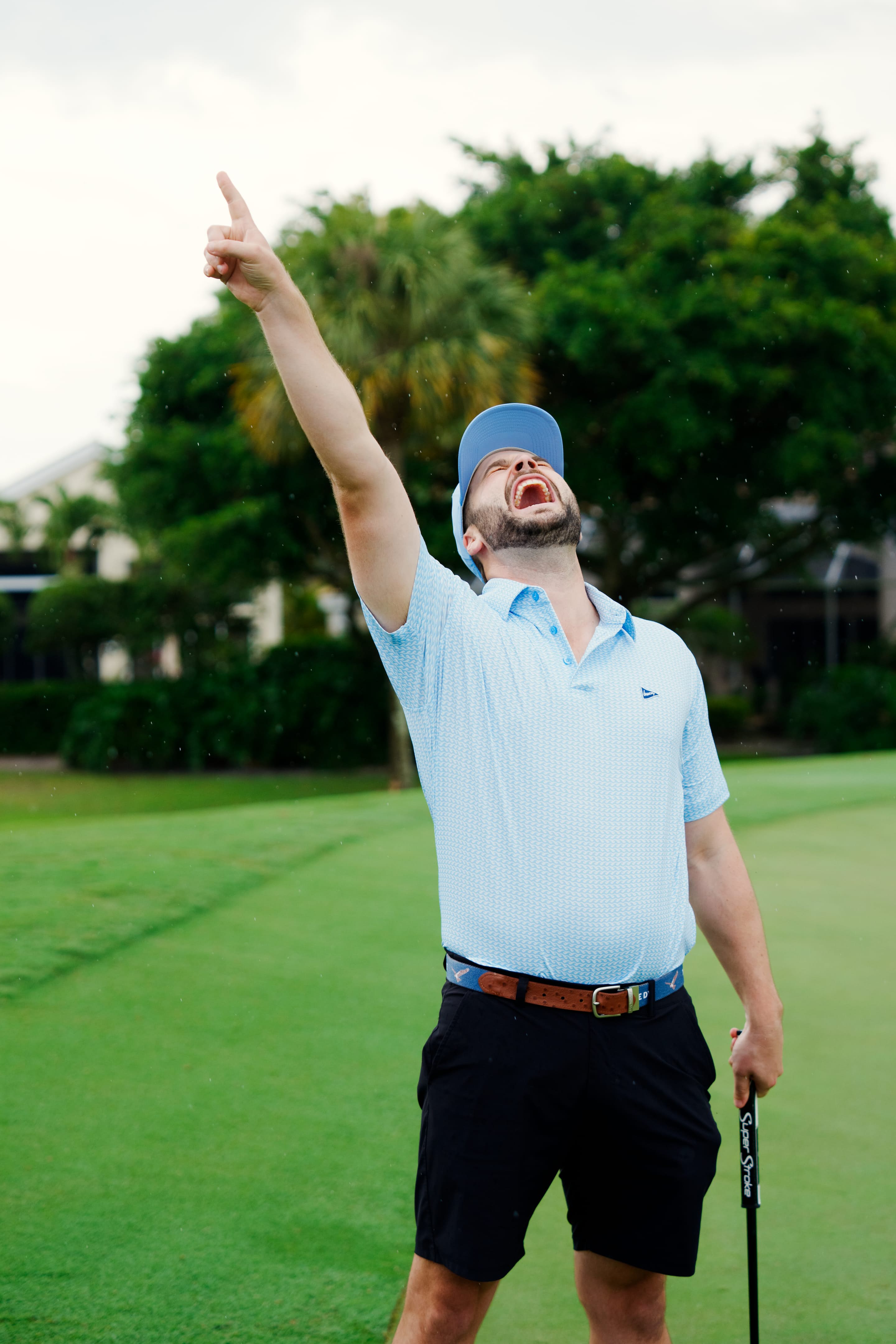 A male golfer pointing his finger in the air in celebration  on a green. 